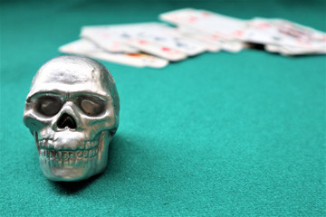 Skull, deck of cards  on a green table. casino table