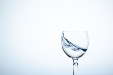 Water splashing in the luxury wine glass close up.  Concept of good healthy and refreshment.  Copy space on left side on the image.