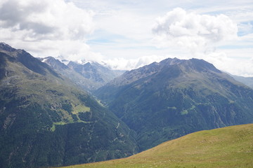 Berglandschaft mit Wolken, Grün, Pflanzen, Felsen und Schnee in Sölden/ Ötztal 