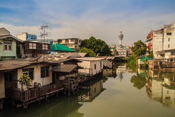 Samut Prakarn observation tower with canal and village in foreground and blue sky background. Samut Prakan is located at the mouth of the Chao Phraya River on Gulf of Thailand.