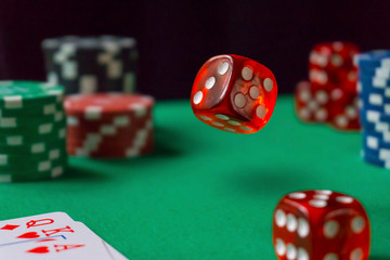 Red dice, casino chips, cards on green felt