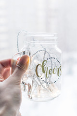 Glass with the garland in the hand. Beautiful decor