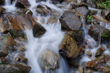 Bachlauf/ kleine Wasserfälle über Steine in den Bergen