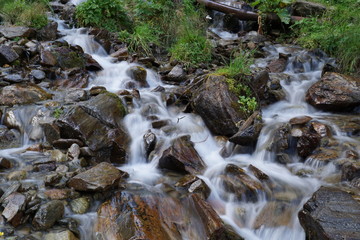 Bachlauf/ kleine Wasserfälle über Steine in den Bergen