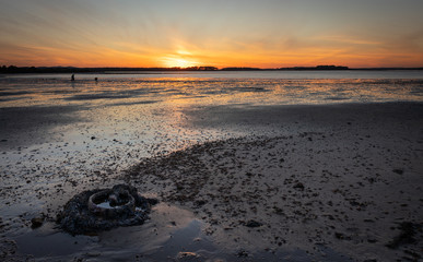 Old metal object rusting in bay in low tide at sunset