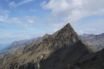 Fototapeta premium Berglandschaft mit Wolken, Grün, Pflanzen, Felsen und Schnee in Sölden/ Ötztal 