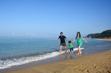 Happy family enjoying on beach. Summer vacation, family with one child having fun and run on beach