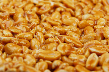 Kozinaki from golden, roasted peanuts beans as a background, texture. Macro shooting, close-up....