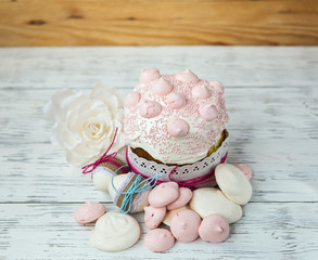 Кулич с бизе, яйцами и цветами на деревянном столе.
