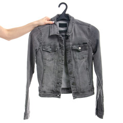 Gray jeans jacket on a hanger in hand. Isolation on a white background.
