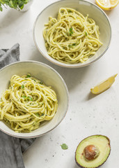 Pasta with avocado and Greek basil sauce in a ceramic bowls on a white table. Dinner for two, copy space.