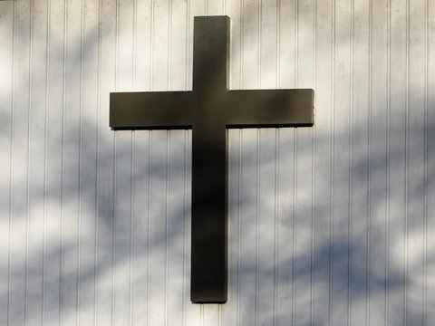 Christian cross on white outside wall of church