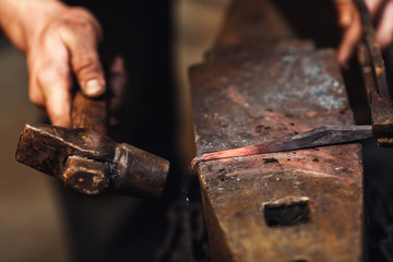 blacksmith makes an artistic forging of hot metal on the anvil.