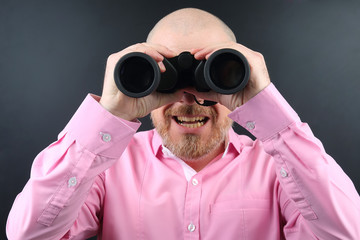 Bearded man looking through binoculars on dark  background