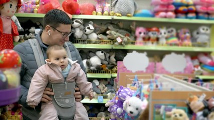 Father with his child in baby carrier in the shopping mall, attachment parenting concept