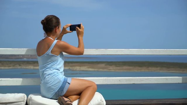 Young tourist woman taking picture of beautiful view over the sea , Sardinia, Italy