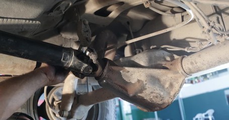 Mechanic repairing cardan. Man placing snap ring using bolt and nut in to fix universal cross joint to cardan joint. Man dirty greace hands appear on the scene