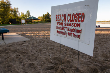 Sign warning swimmers that the beach is closed for the season, water quality is not tested. Taken in fall