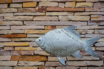 Fishes and pattern of old decorative stone wall background. Vintage stone wall Texture in weathered and have fish sculptures for design background. Featured pattern gray color of antique stone wall.