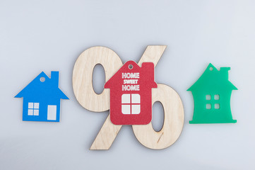 wood percent sign and house shape on white background. The concept of price changes on the real...