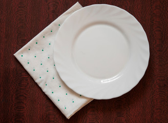 Empty plate on colorful tablecloth in an old wooden table