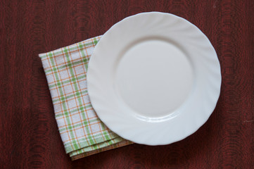 Empty plate on colorful tablecloth in an old wooden table