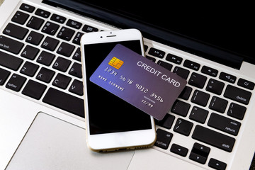 Credit Card put on mobile phone and laptop keyboard for preparing to pay