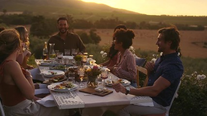Group of man and women laughing at dinner party. Millennials enjoying at party in evening out in the yard.