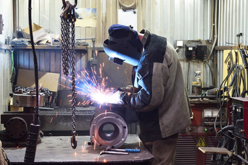 The base for the valve is mounted on the iron table at the factory and the worker welds with a...