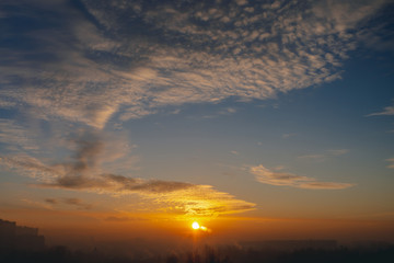 Sunny shine on clouds. Wonderful vivid dawn. Beautiful calm orange sunset. Scenic urban sunrise. Amazing cloudy sky. Picturesque sundown. Atmospheric cloudscape. Circle of sun above city horizon.