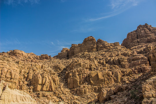 desert bare steep rocks foreshortening from below on vivid blue sky background 