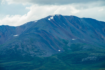 Amazing giant mountain with snow on top in mist in overcast weather. Huge snowy mountain in haze under cloudy sky. Atmospheric misty mountainous landscape of majestic nature. Wonderful mountainscape.