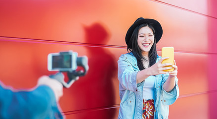 Asian fashion woman vlogging and using mobile smart phone outdoor - Happy Chinese trendy girl having fun making video with gimbal camera - Millennials people, Generation z and technology concept