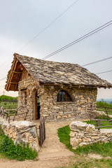 Fototapeta na wymiar Stone cabin April exterior view, schist roof tiles, in Bulgaria