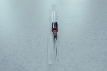 Syringe with red solution on white background