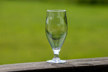 Empty glass of beer on green nature background.