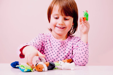 Finger puppet theatre. Cute little child girl playing with toys of animals. Happy childhood concept.