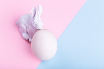 Easter rabbit and white egg on a pink-blue background, concept Happy Easter