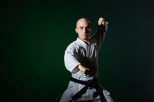 In karategi, an athlete perfom formal karate exercises on a dark green background