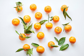 Group of orange fresh tangerines with green leaves lie on a white background.