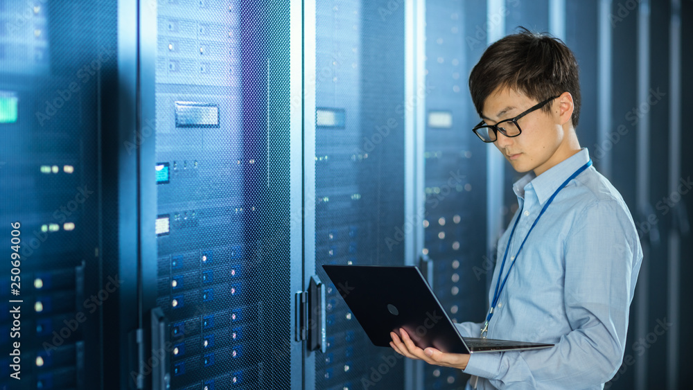 Aufkleber in the modern data center: it engineer standing beside server rack cabinets, does wireless maintenan