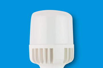 One new plastic led bulb in center on blue background. Top view