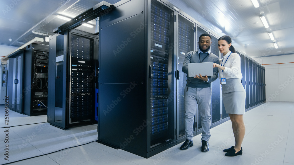 Aufkleber Black IT Technician with a Laptop Computer Gives a Tour to a Young Intern. They Talk in Data Center while Walking Next to Server Racks. Running Diagnostics or Doing Maintenance Work. 