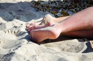 Legs at the beach covered with sand