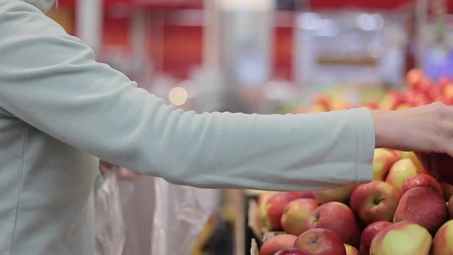 Woman in the fruit market with apple in hand.