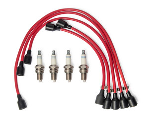 Four spark plugs and red wires of a high pressure are isolated on white background. Car parts. Top...