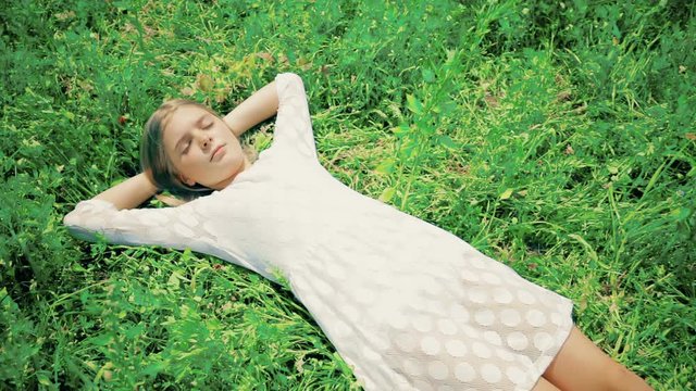 Girl enjoying life in nature. Top view jib shot over a girl in grass in focus standing up and go away.