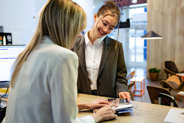 Confident beauty recepcionist showing the rates of their services to a female client in reception of the hotel.