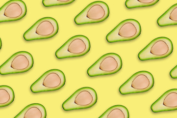 Lots of scattered tasty fresh halves of organic avocado with kernels on yellow table in kitchen or market. Top view. Cooking concept