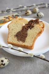 Easter homemade cupcake with chocolate bunny on a white plate in the background quail eggs and willow branches